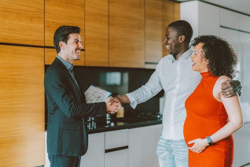A couple and agent shake hands after a house tour.