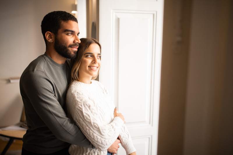 Couple embraces at doorway in their newly purchased home.