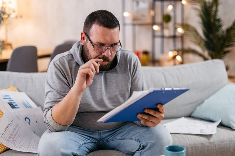 A self-employed man checks documents regarding a mortgage refinance.