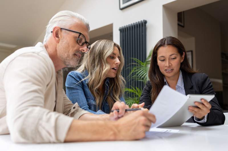 Mortgage banker talking to a couple about the documents needed to get a home loan and buy a house.