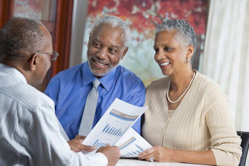 Senior couple discussing with a financial advisor whether they can get a mortgage or refinance on Social Security retirement benefits.
