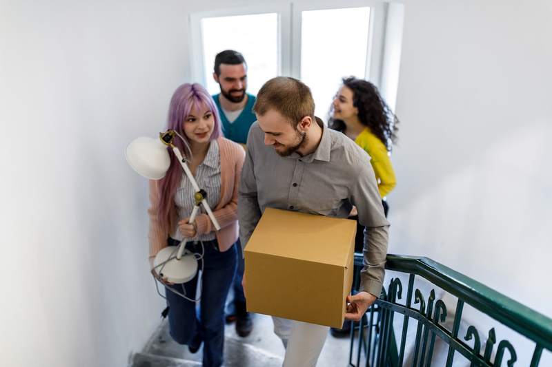 Friends move furniture and boxes into a home.