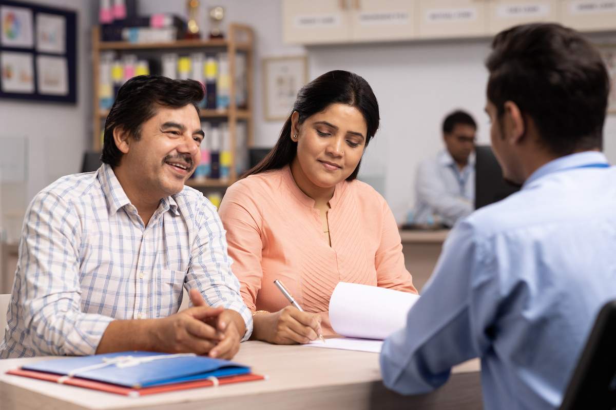 A man and woman sign refinance documents with a lender.