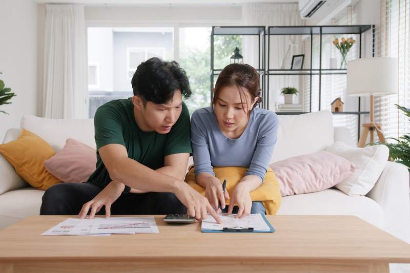 A man and woman sit on a sofa and compare notes on mortgage types.