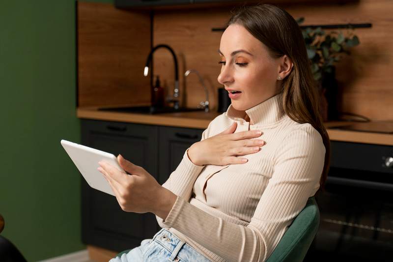 A woman holding a tablet computer responds to news about her house offer.