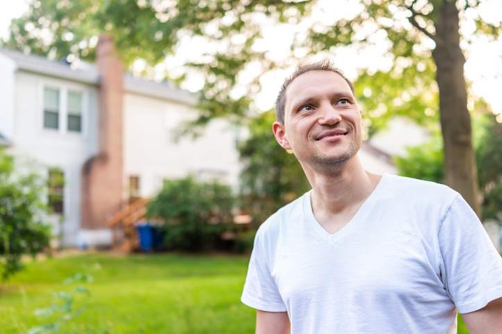 Man smiles in a home's large backyard.