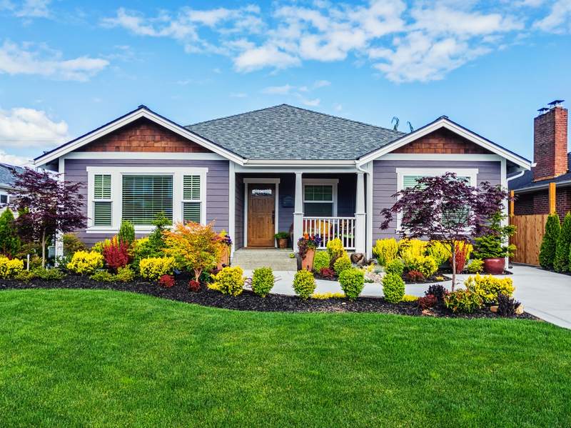 Exterior front view of house overlooking lawn and shrubs.