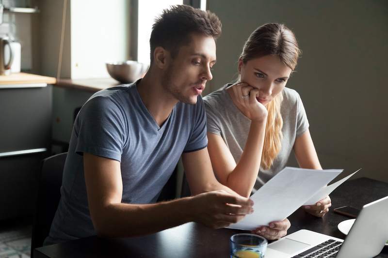 Couple reviews mortgage documents at kitchen table.