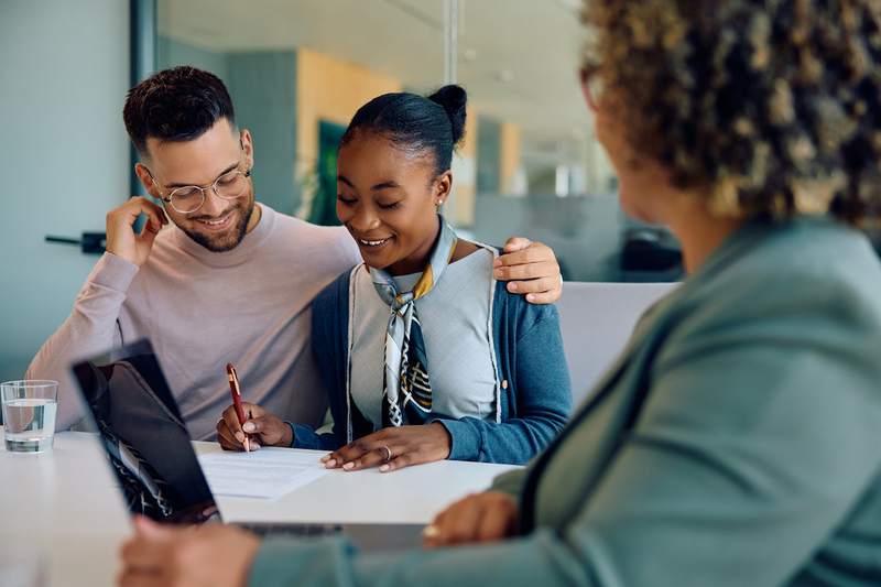 Couple signs paperwork on a second mortgage refinance with a loan officer.