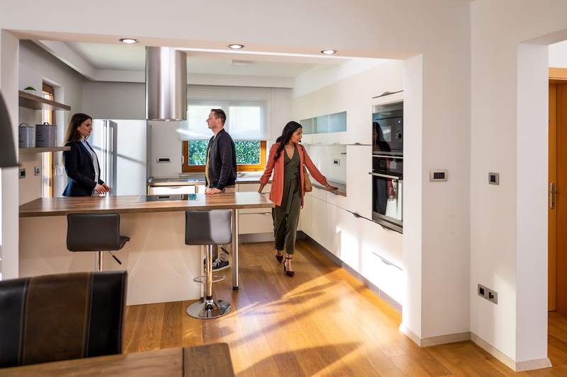 Owner shows prospective buyers the kitchen of the home they are selling.