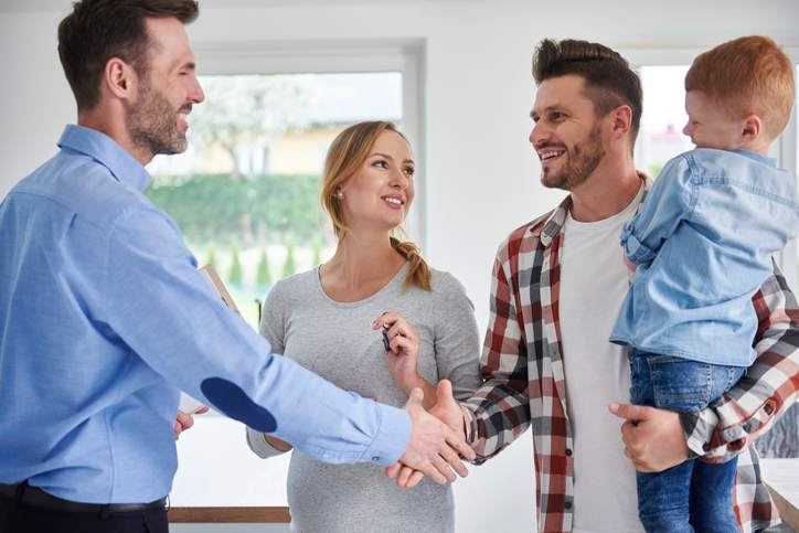 Family and real estate agent shaking hands in new apartment.