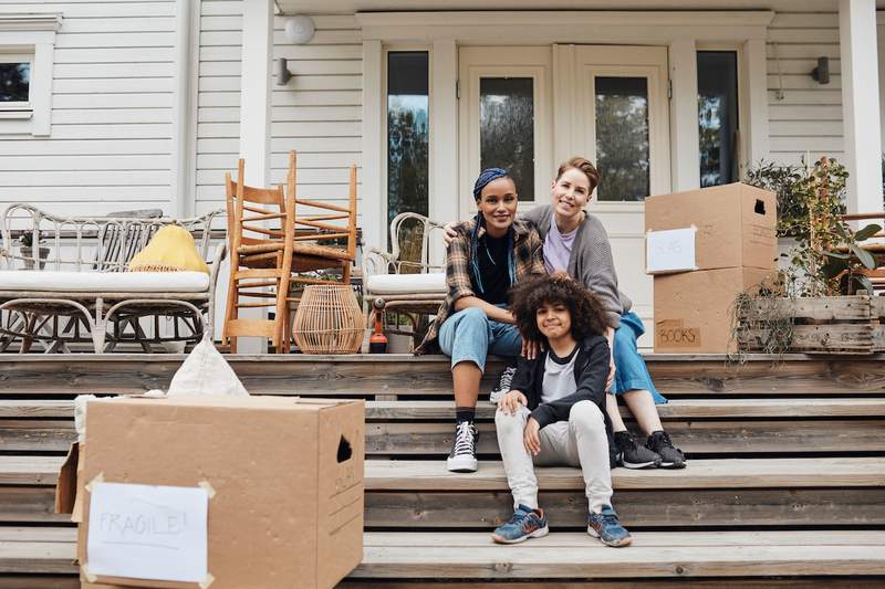 A family sits in front of their new home.