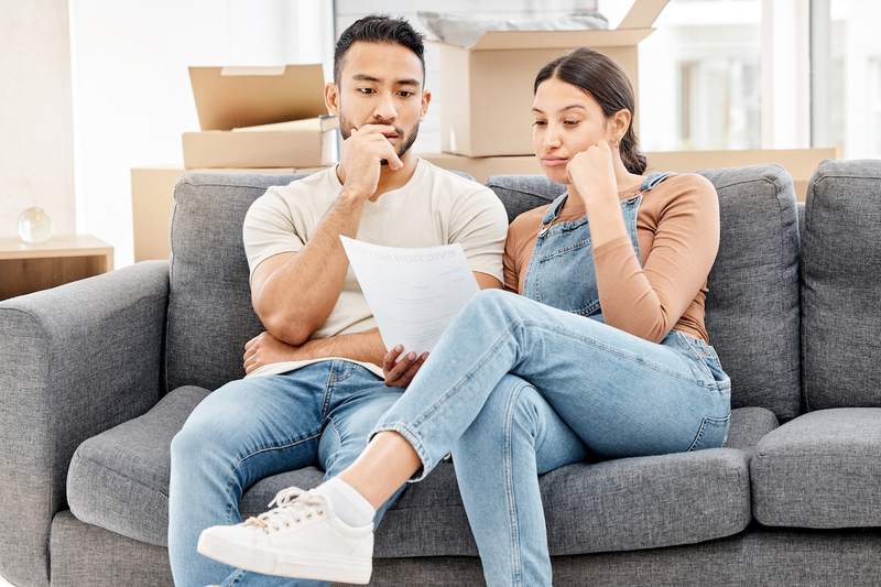Couple sits on sofa and reviews financial documents.