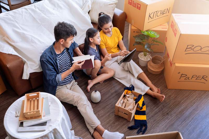 Couple and daughter relax amid moving boxes in new home.