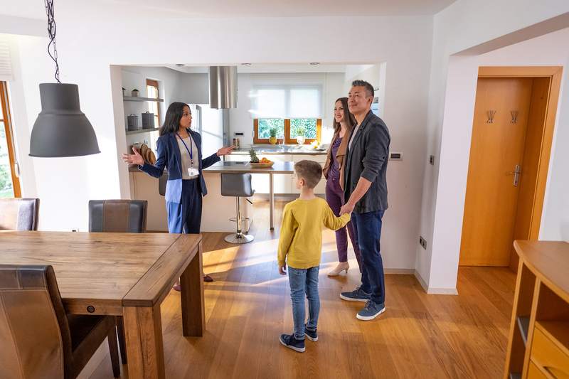 A real estate agent shows a family a home with a large, bright kitchen.