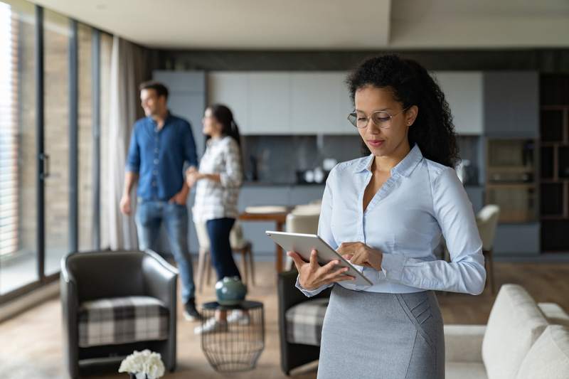 Real estate agent reviews tablet for a couple under contract.