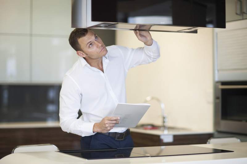 Man inspects kitchen appliances.