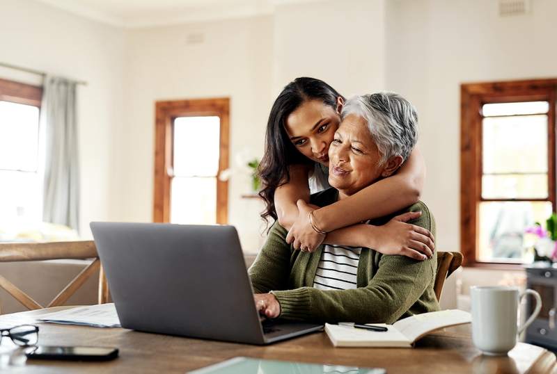 Woman hugs grandmother while reviewing mortgages.