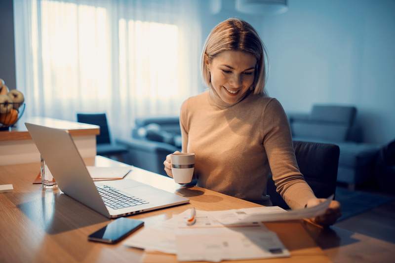 A woman sitting at a kitchen tables reviews her home equity loan documents.