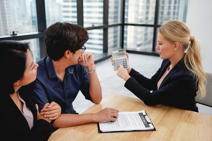 Couple looking at adjustable mortgage rate papers with loan officer