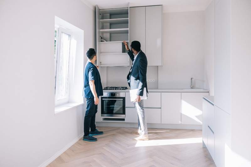 A young man asks about the cabinets on a house tour.