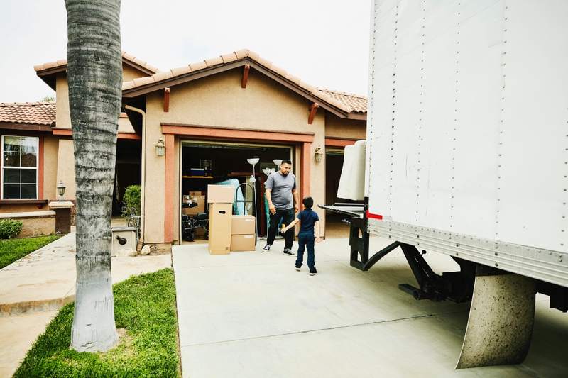 A father and son unload boxes from a moving truck.