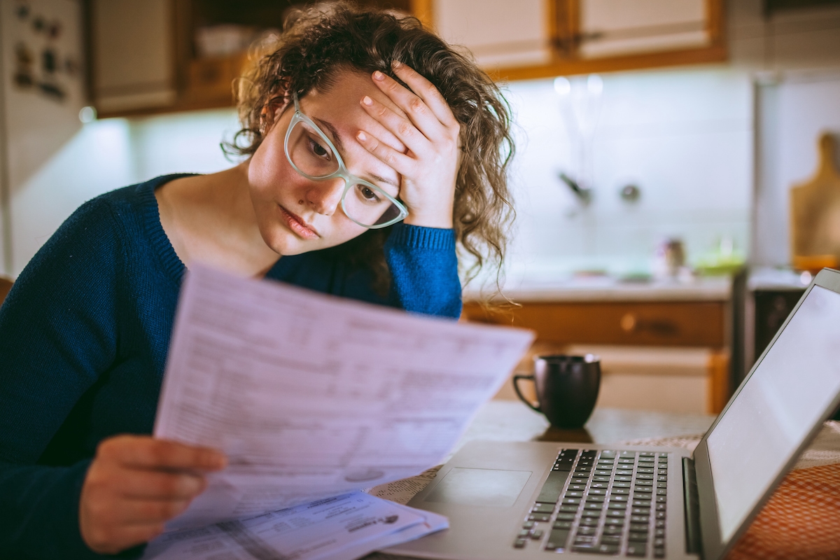 Stressed woman reviews financial papers for mortgage loan modification.