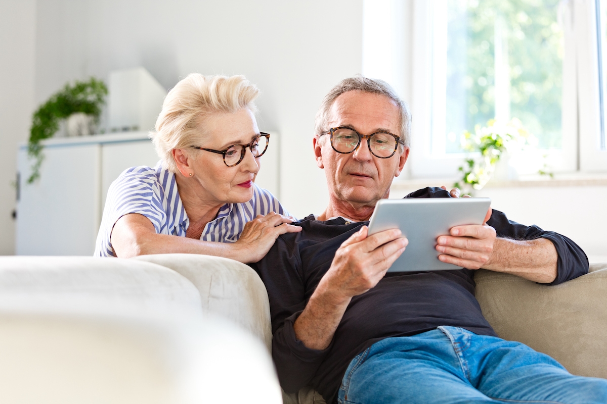 Older couple on a tablet in the living room at home, reviewing their eligibility for a reverse mortgage.
