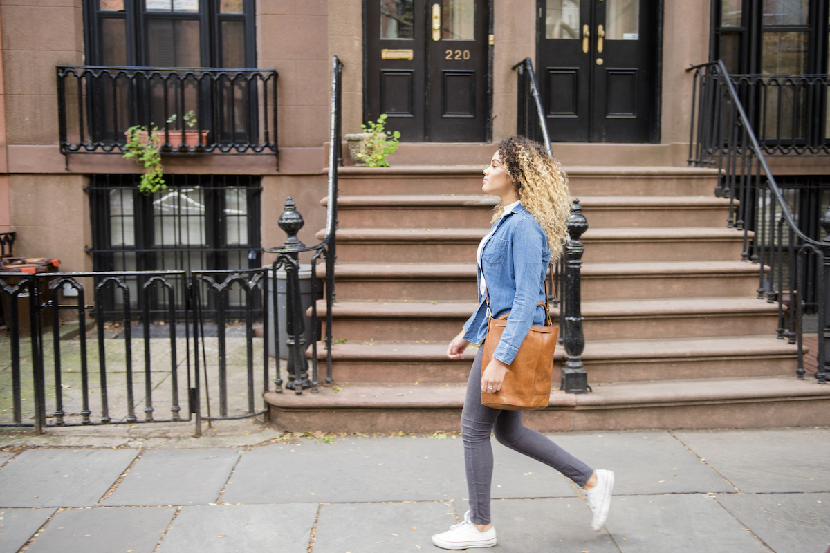 A woman walks past a brownstone stoop.